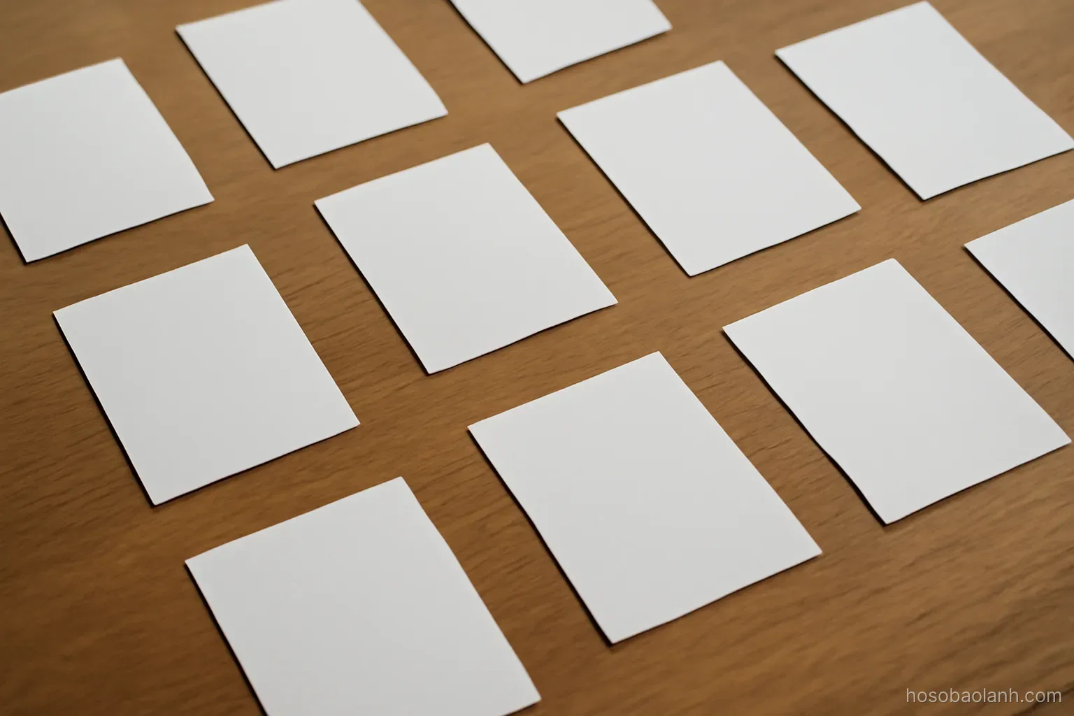 printed photographs spread face down on a table in a loose grid, overhead view, backs blank