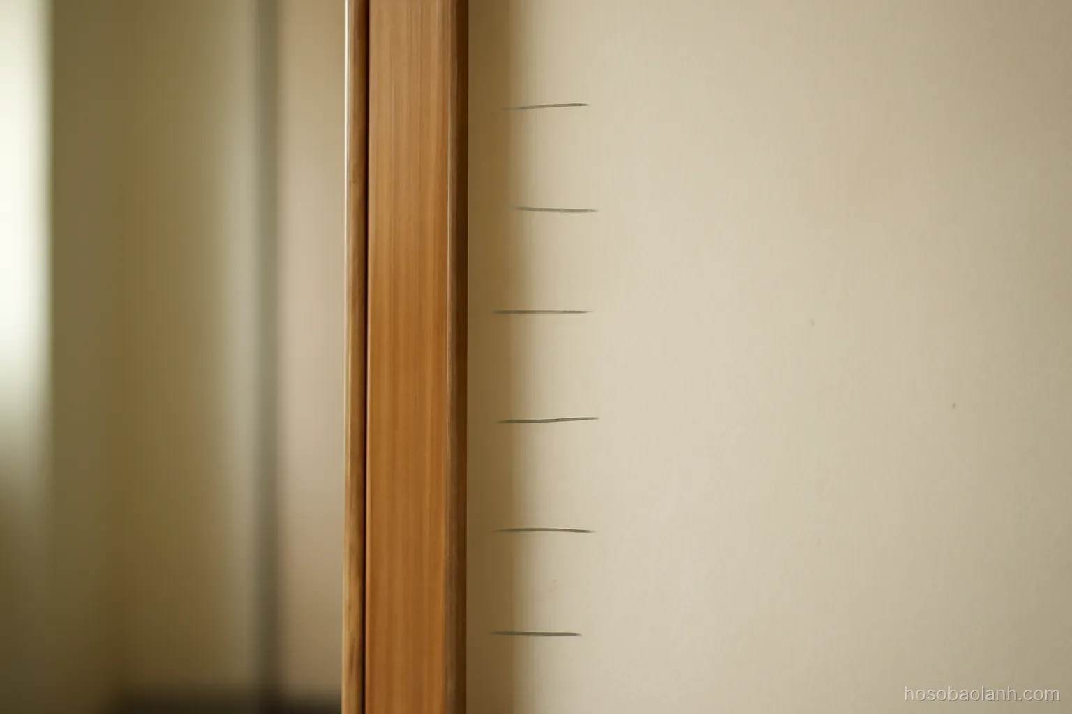 a doorframe with pencil height marks at different levels, plain painted wall, no writing visible