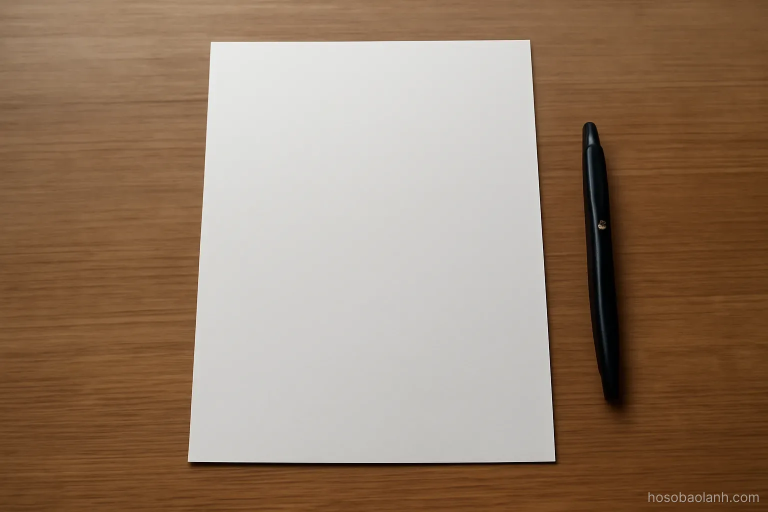 a single clean sheet of paper on an otherwise empty desk beside a closed pen, top down view